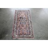 An approx. 4'7" x 2'3" pink and blue pattern rug