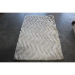 An approx. 5'7" x 3'6" cream pattern rug