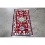 An approx. 4'4" x 2'2" red and blue pattern rug