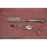 A silver butter knife and a pair of silver sugar n