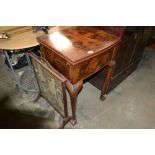 A walnut sewing machine table lacking sewing machi