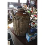 A stoneware jar with cork bung in wicker two handl