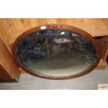 An oval mahogany framed and bevelled edge mirror
