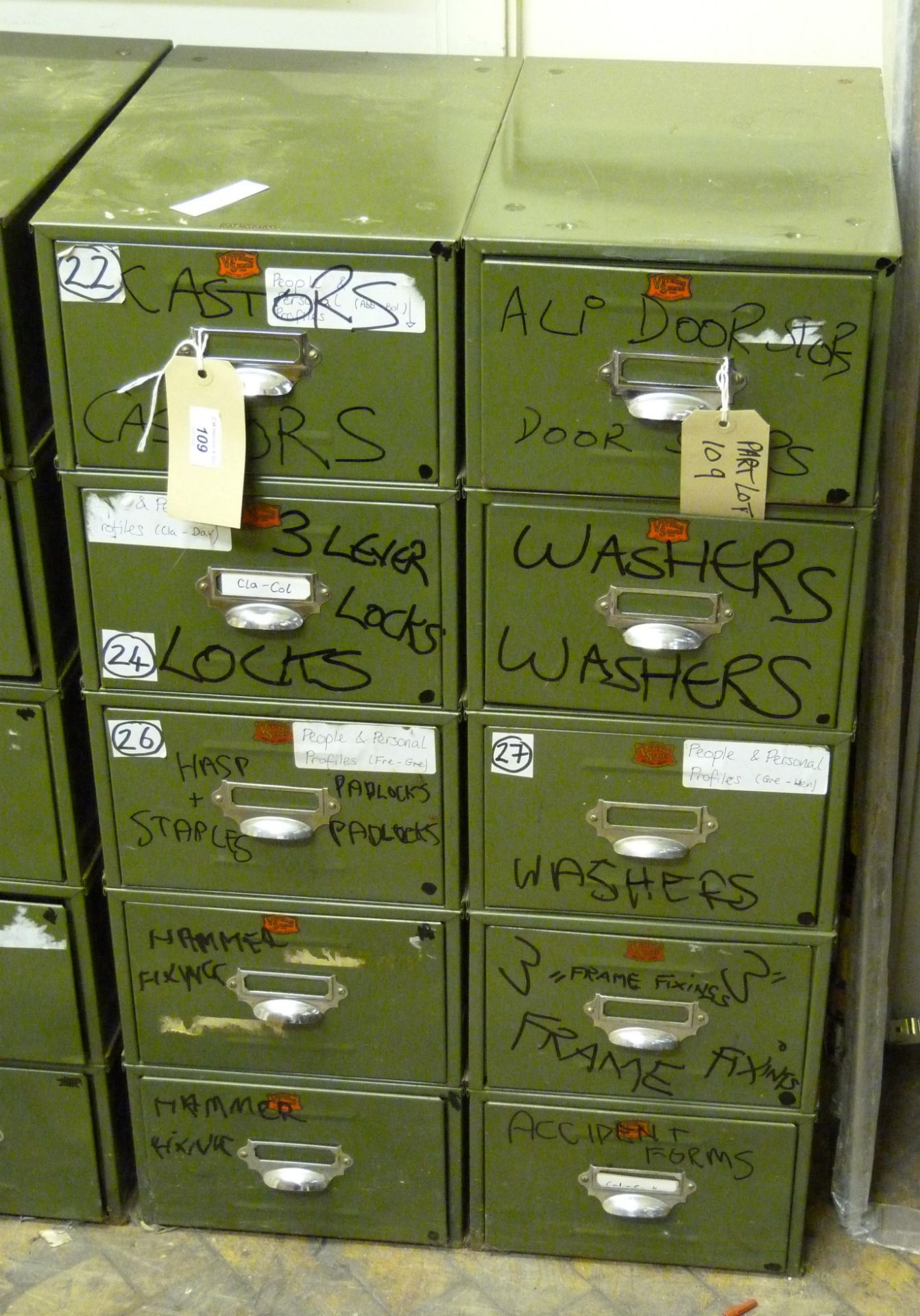 Two Veteran Series green metal five drawer units and contents to include castors,