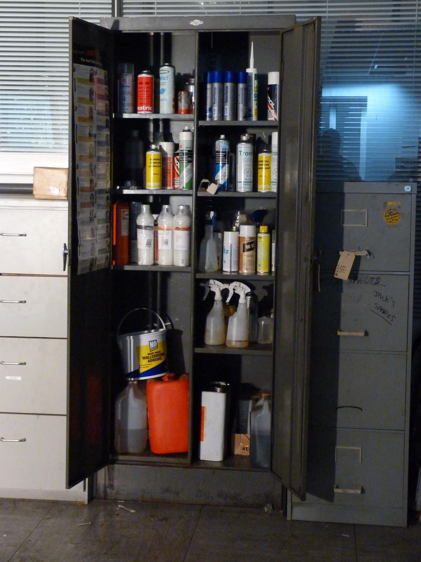 A double door cupboard and contents to include lubricants,