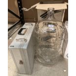 A 23 litre glass wine bottle and an aluminium case (2)