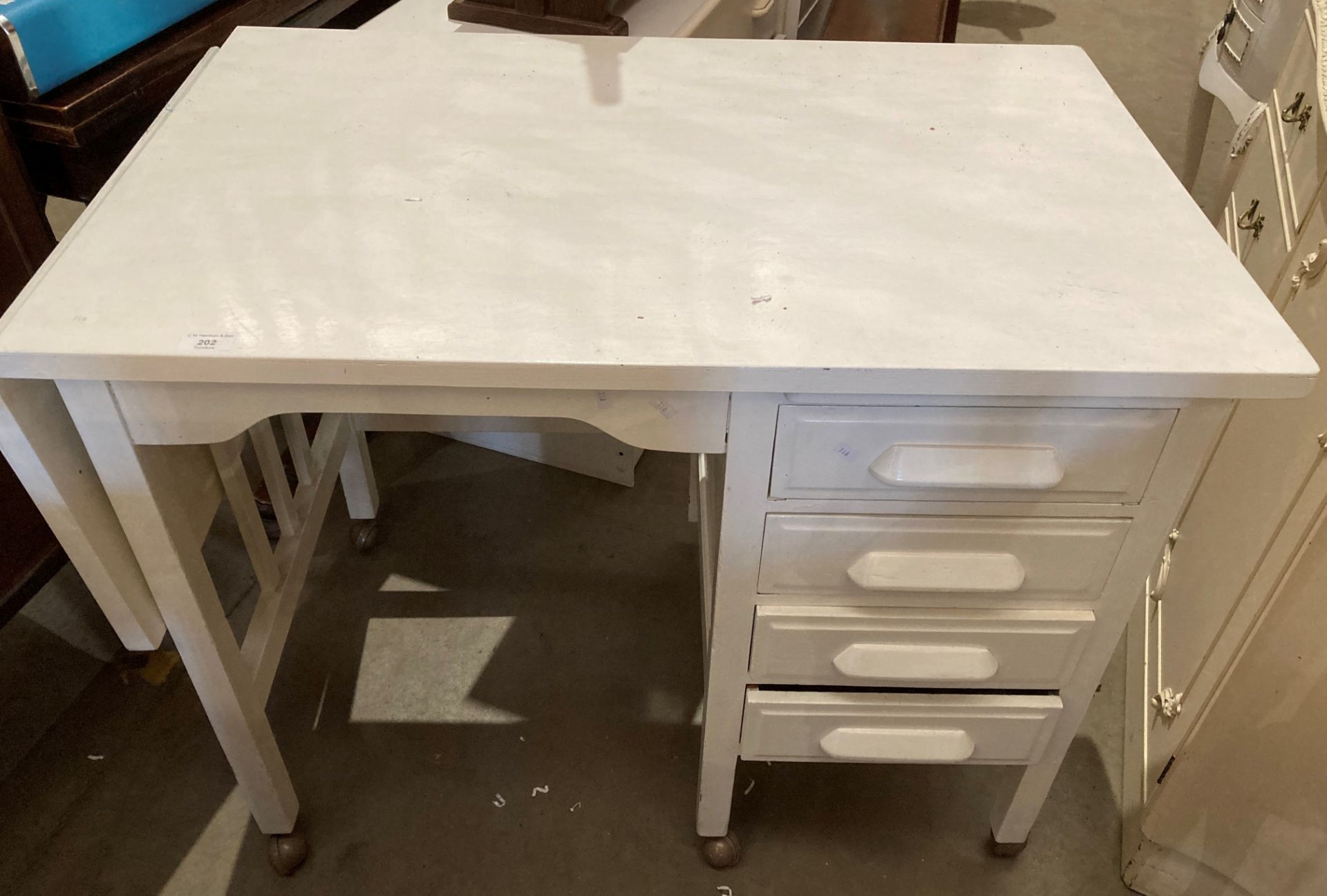 A white painted four drawer single pedestal desk with fall flap to side 92cm x 58cm plus flap 30cm