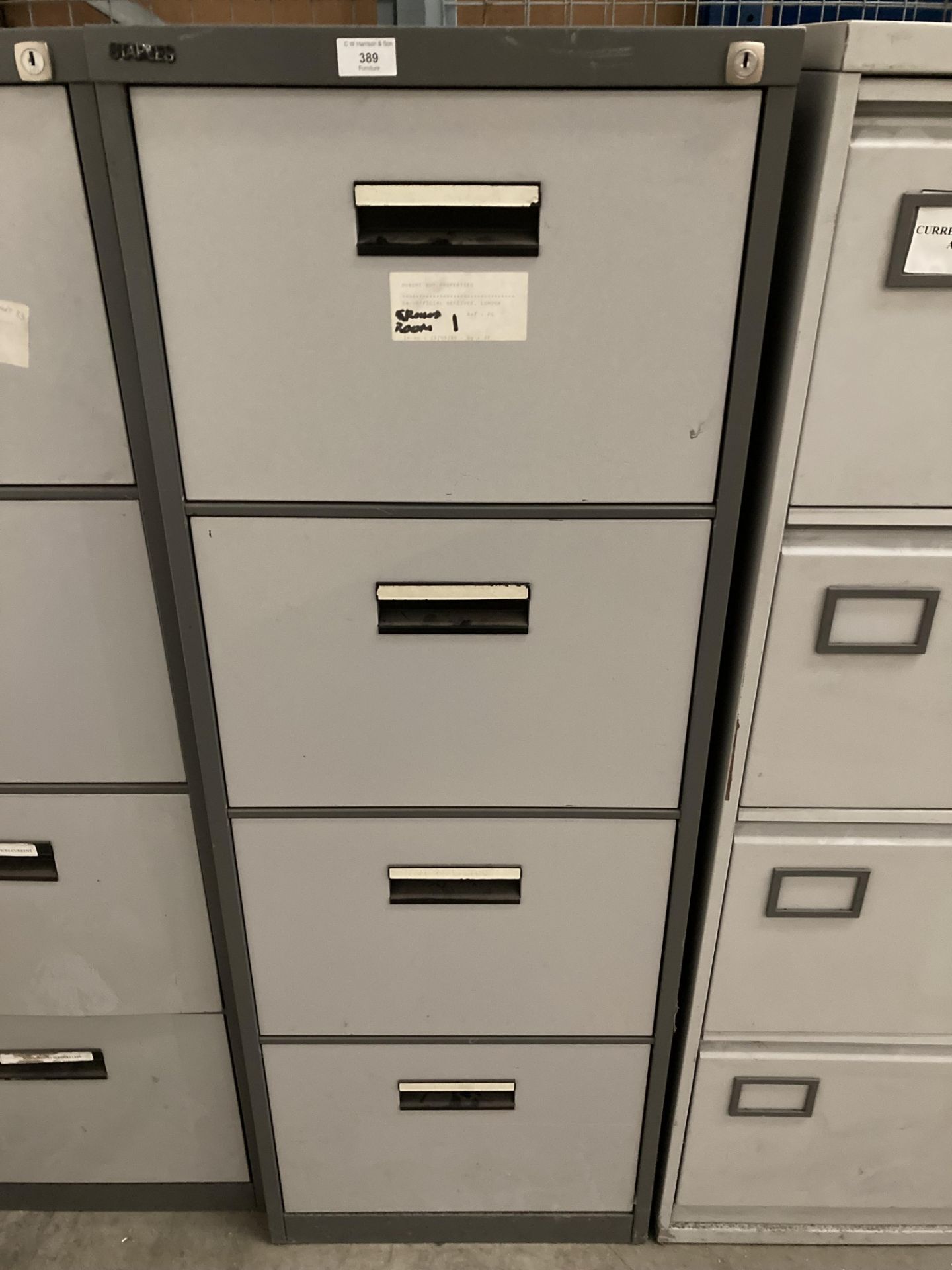 A grey metal two tone metal four drawer filing cabinet