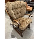 An oak cottage style rocking chair with brown patterned upholstered seat and back cushions.