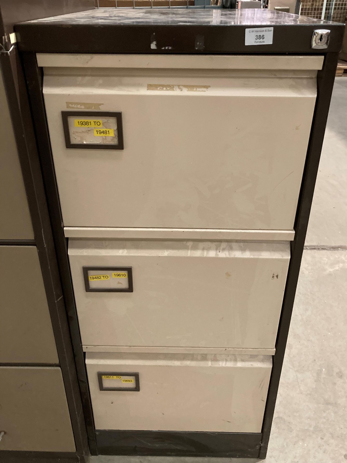 A brown and beige metal three drawer filing cabinet