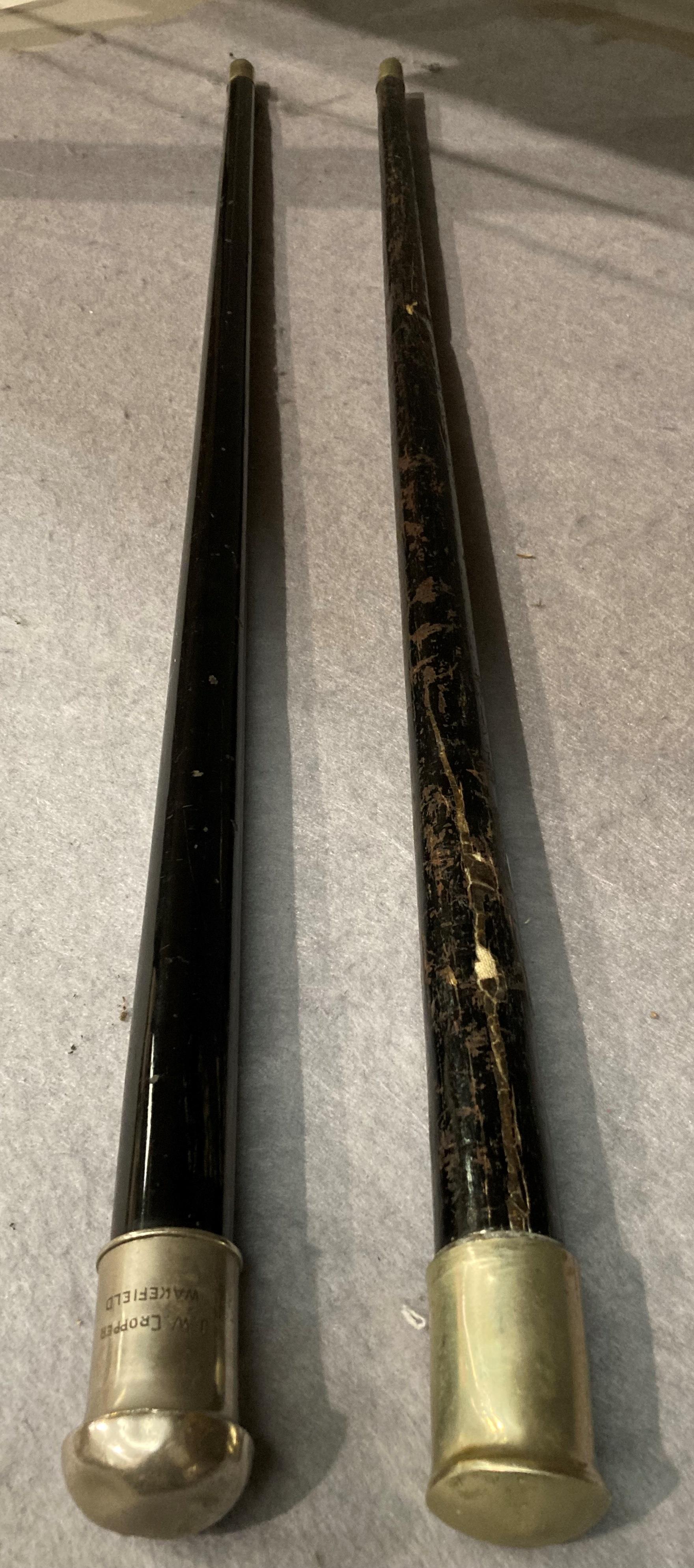 Two ebonised walking sticks (hollow interior) with silver coloured handles one inscribed 'J.