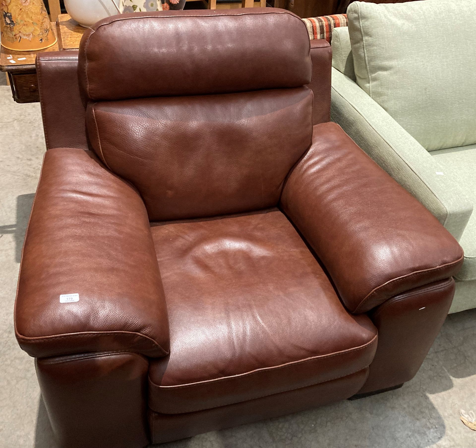 A dark brown leather wide arm armchair