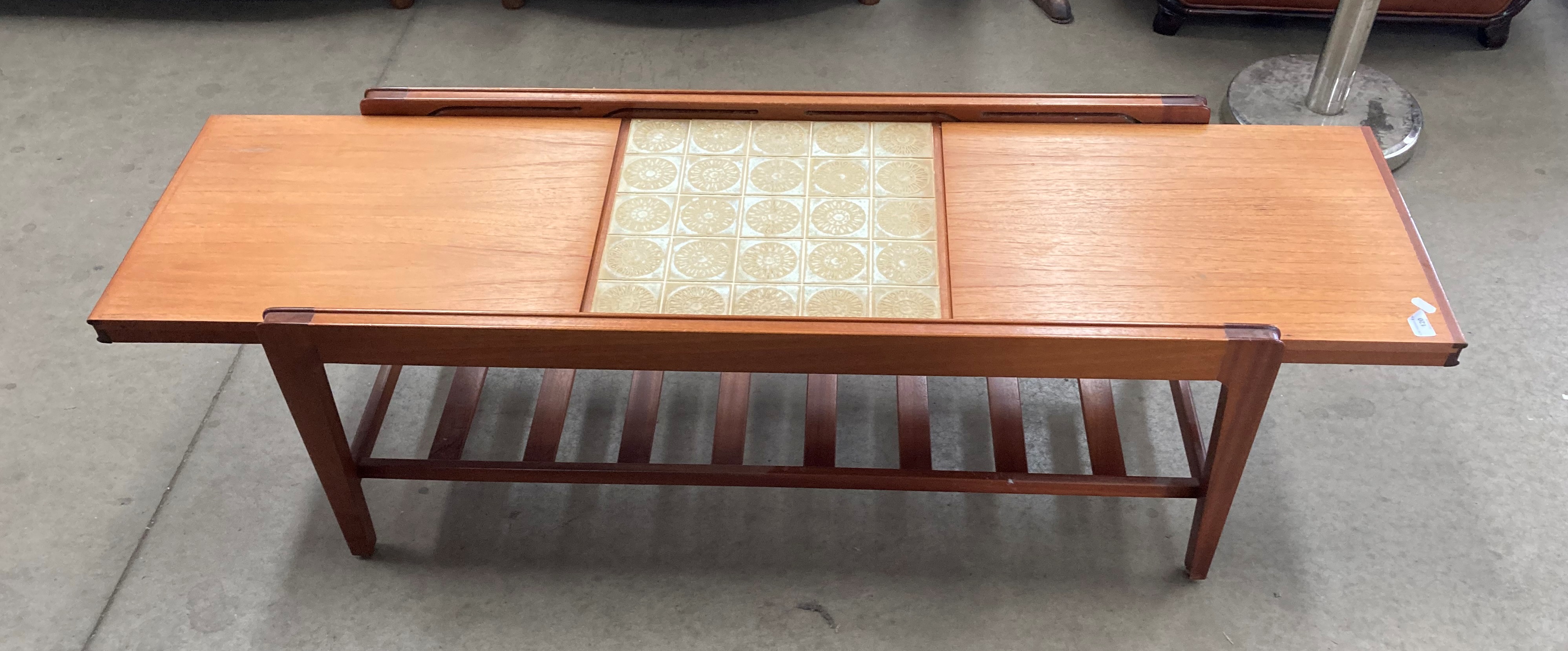 A teak extending top coffee table - when open it reveals a brown patterned tiled centre section