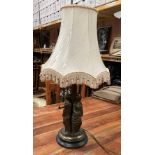 A brass table top lamp with three ladies holding lamps on wood base complete with ivory coloured
