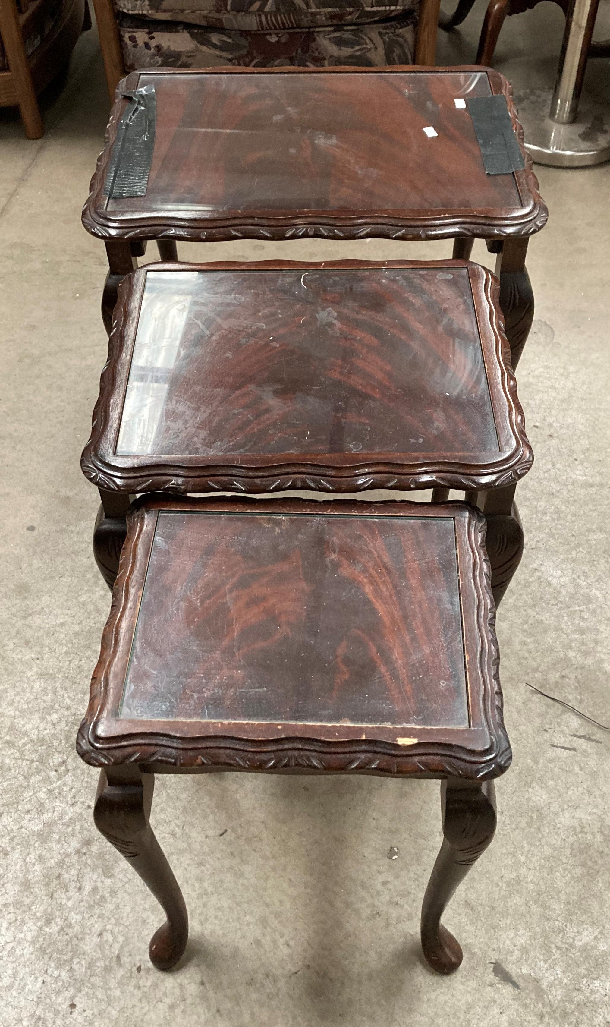 A nest of three mahogany coffee tables with glass inset tops