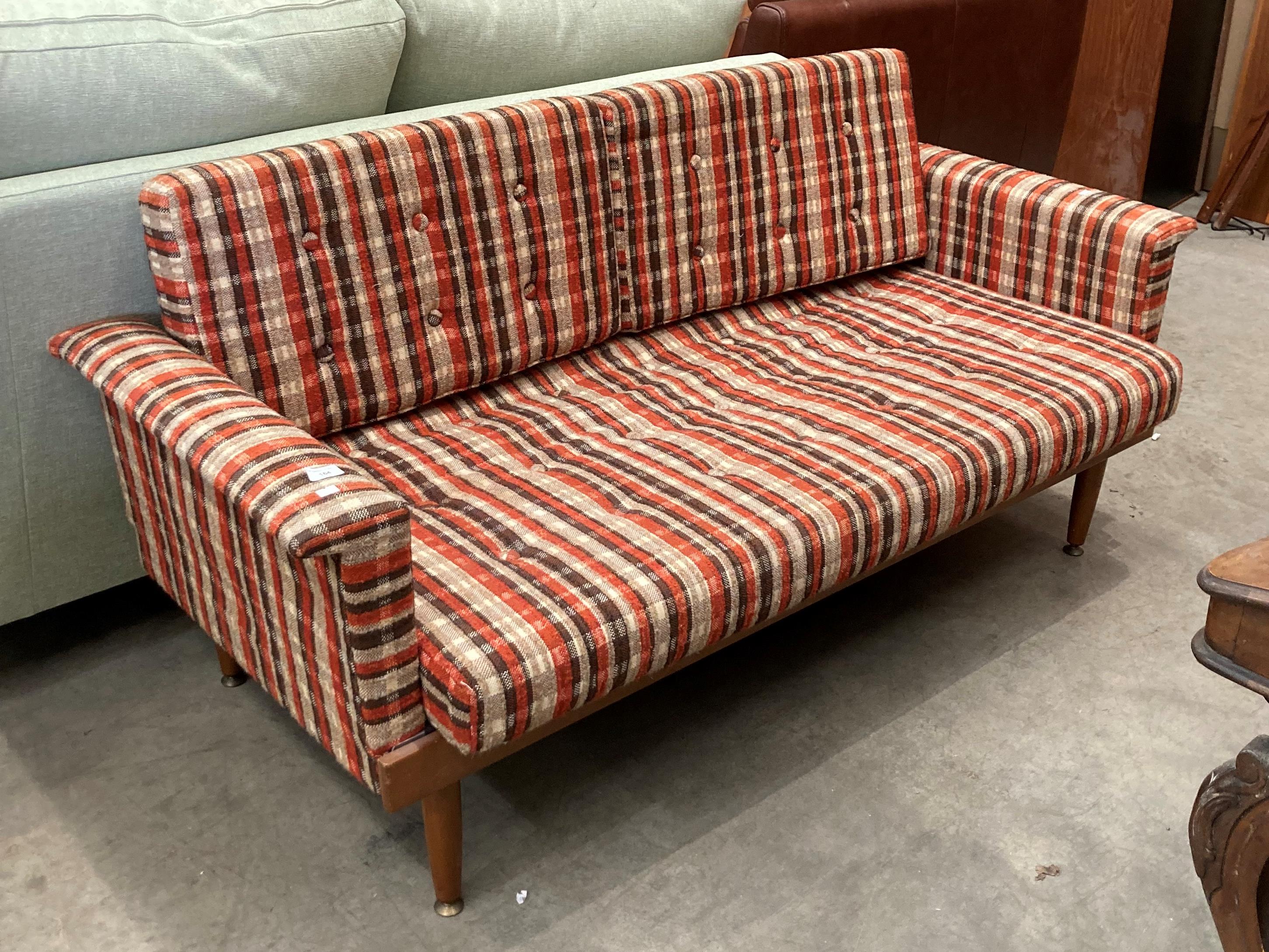 A mid Twentieth Century teak framed bed settee with brown/red and ivory patterned upholstery -
