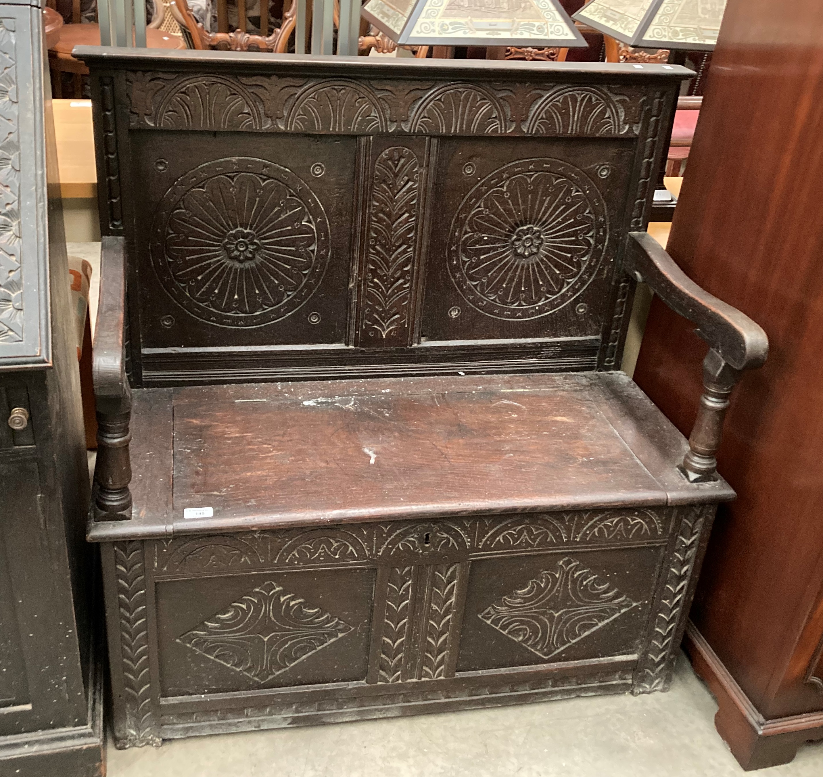 A carved oak settle with lift top seat,