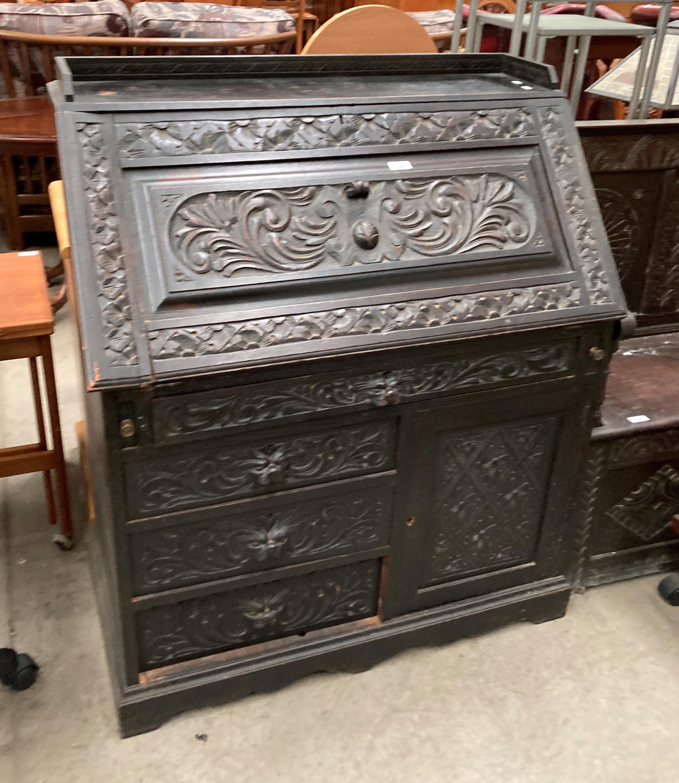 A carved oak bureau with fall flap over four drawer single door base 96cm x 114cm high (part of