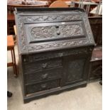 A carved oak bureau with fall flap over four drawer single door base 96cm x 114cm high (part of