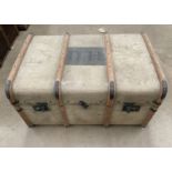 A wood framed light brown fibre upholstered trunk initialled DH,