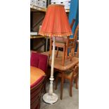 A cream painted wooden standard lamp with orange shade