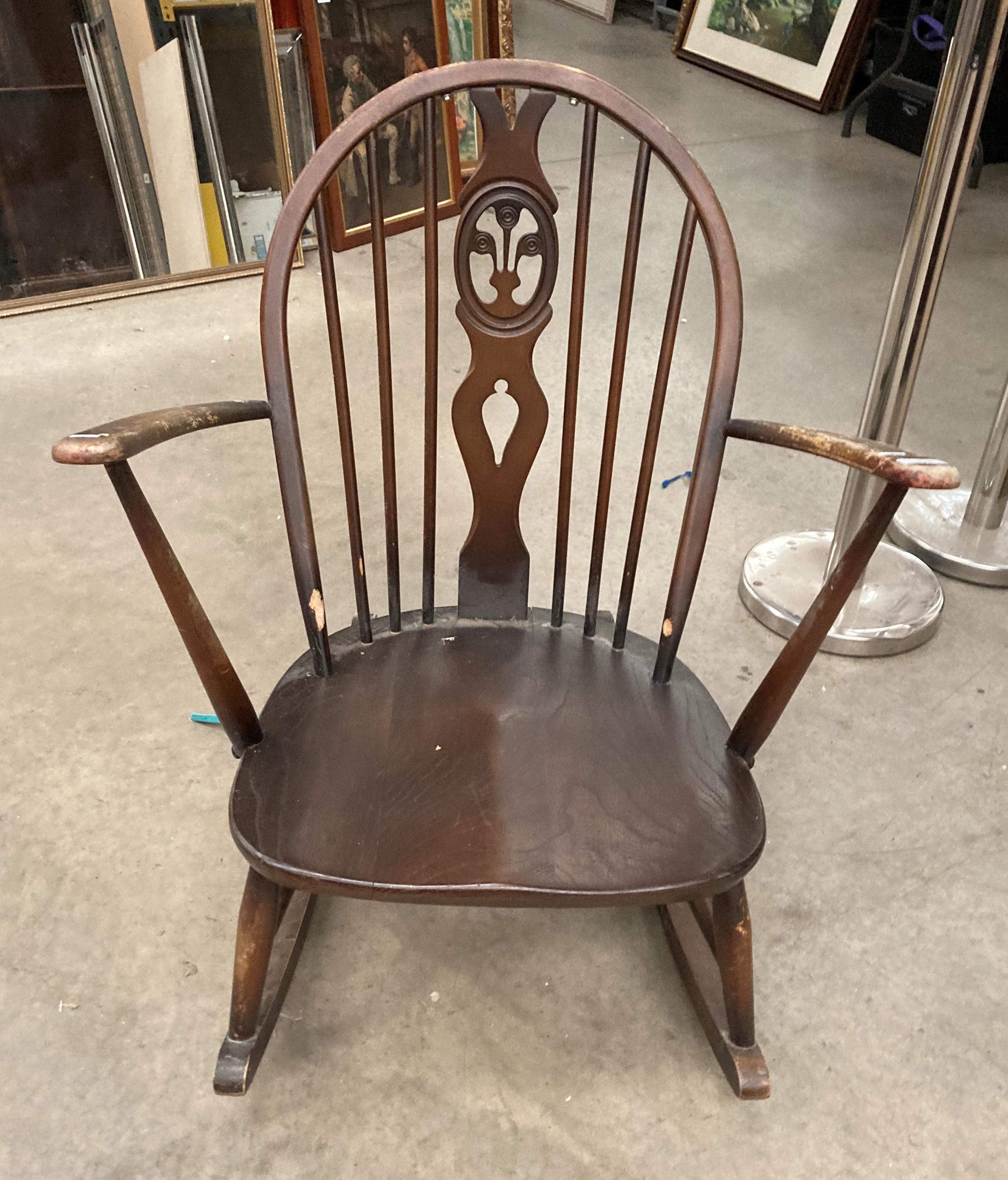 An Ercol medium wood rocking chair - repair to top rail and worn in places