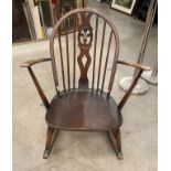 An Ercol medium wood rocking chair - repair to top rail and worn in places