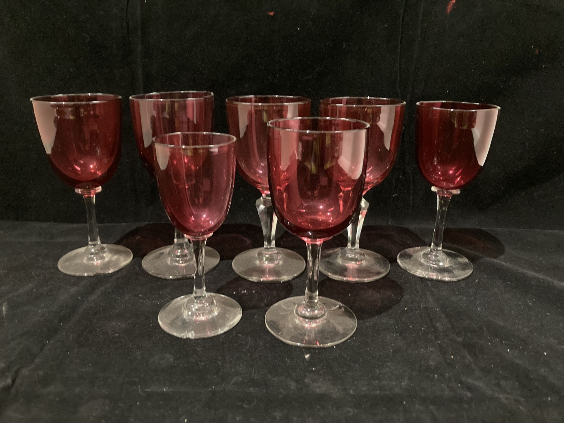 Two cranberry wine glasses with cut glass stems,