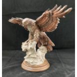 A resin model of a bird of prey mounted on a rock and wood mount 23cm high x 35cm long