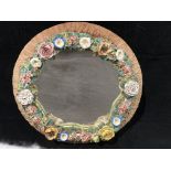 A circular porcelain Meissen style wall mirror with encrusted floral decoration 33cm diameter,