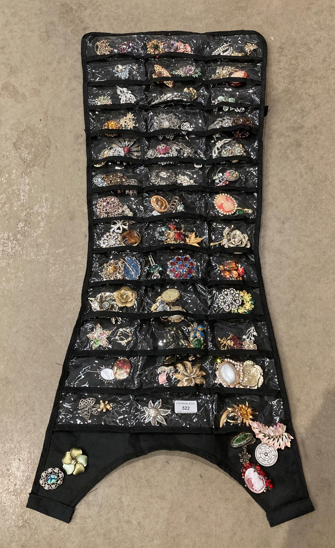 Roll up bag holder with large quantity of assorted brooches.