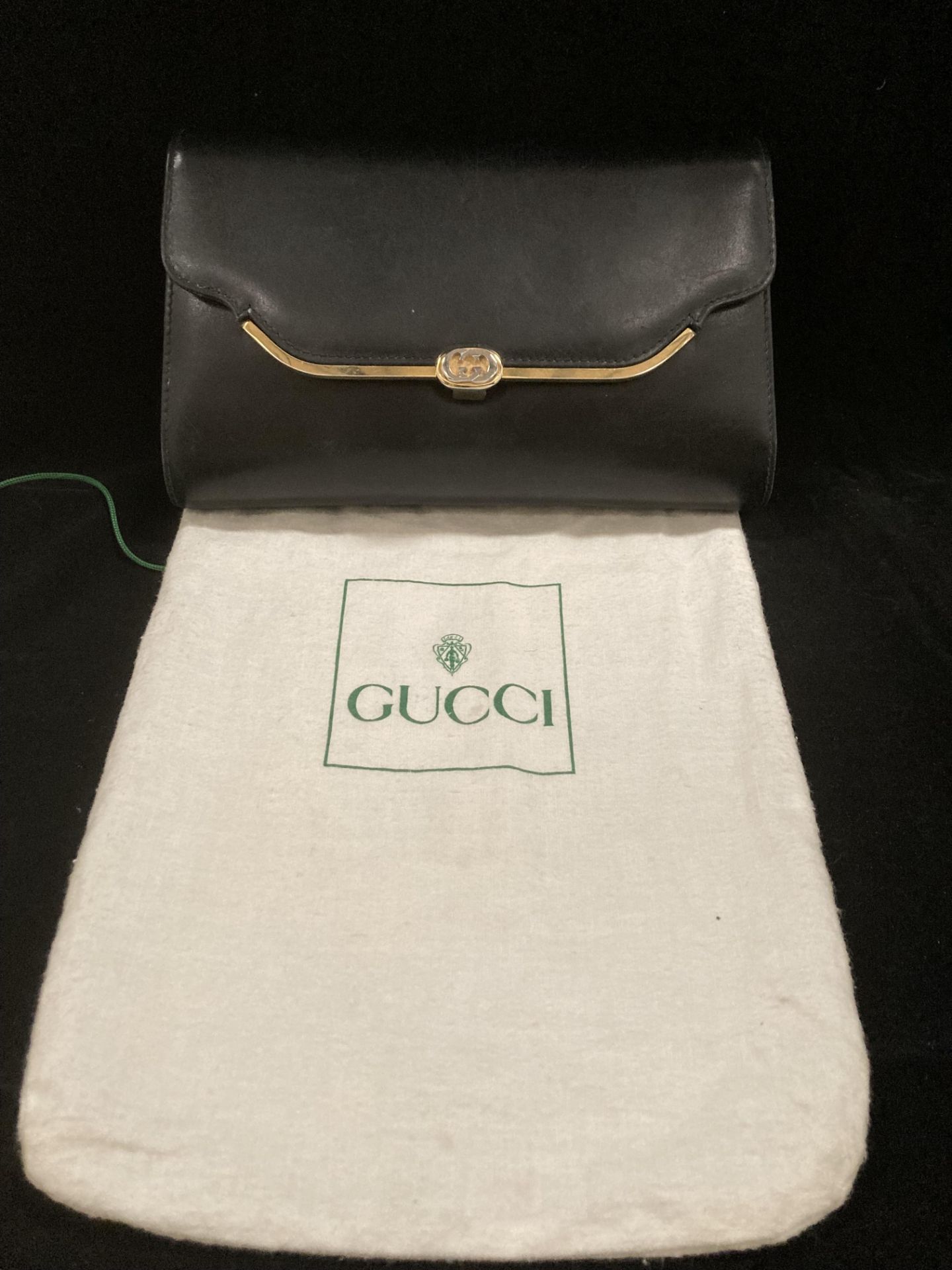 A Gucci black leather clutch bag including a long strap and protective bag.