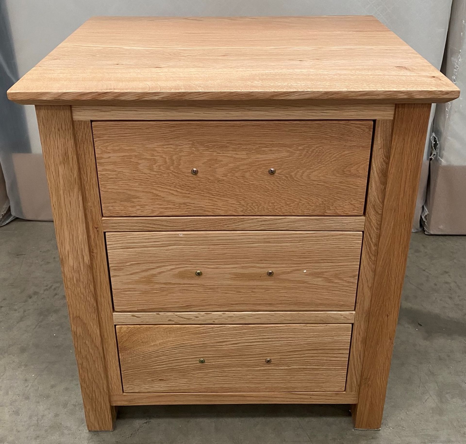 A boxed three drawer oak bedside cabinet 50cm x 40cm x 56.