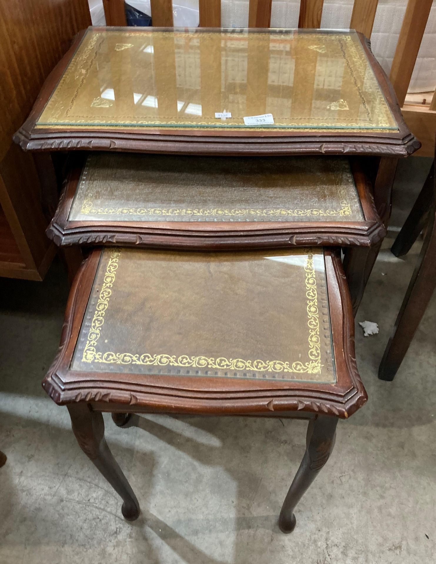 A mahogany finish nest of three coffee tables with brown tooled leather finish tops and glass