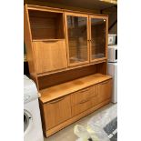 A teak wall unit on castors with two glazed upper doors and fall front cabinet over two drawer two