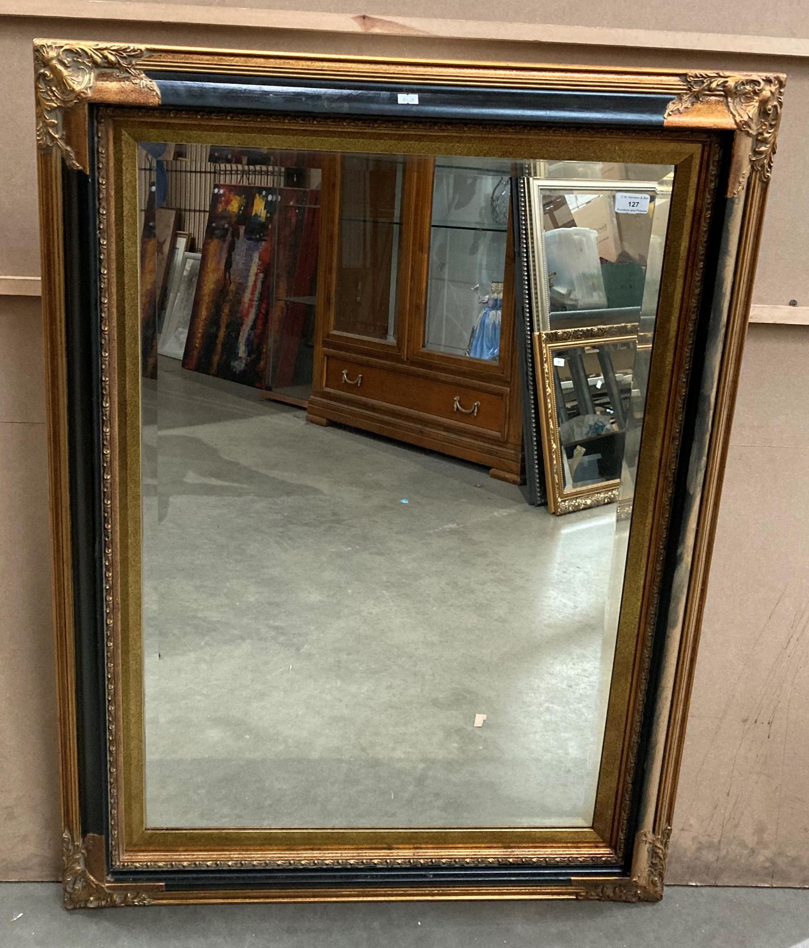 An ornate gilt and ebony effect famed wall mirror,