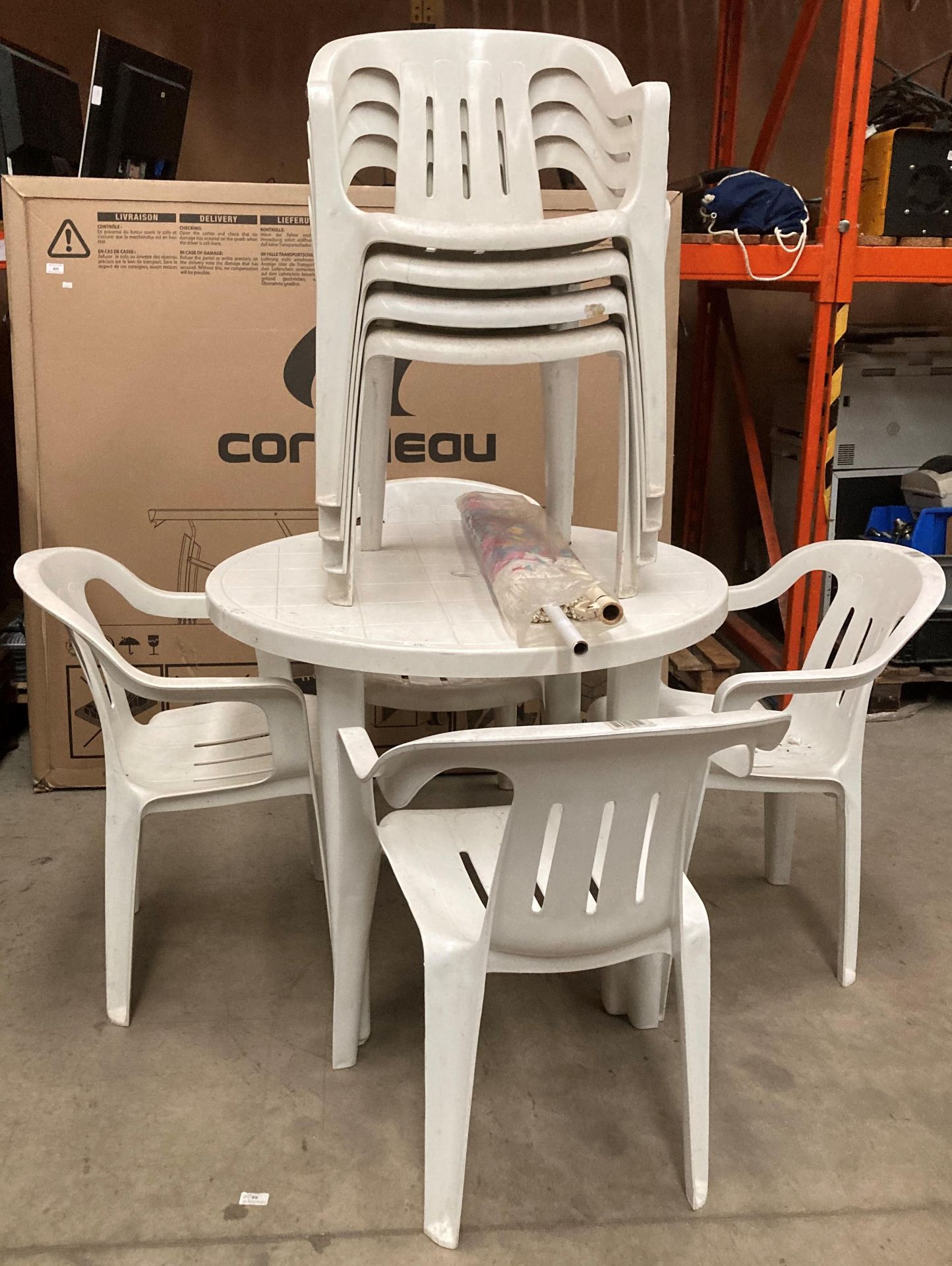 White plastic circular patio table complete with floral parasol and eight stacking plastic