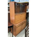 A teak cabinet with glass sliding doors over fall front two drawer two door base,