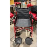 A Remploy red metal framed four wheel wheelchair with foot rests.
