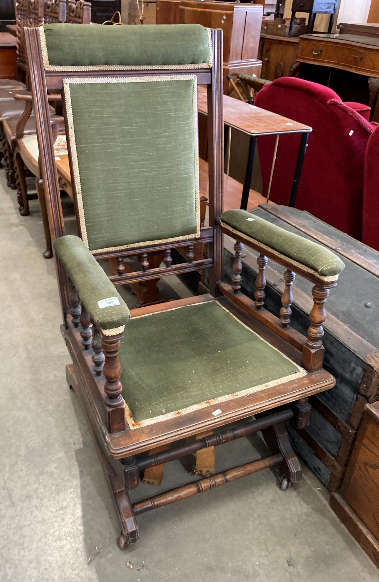 A stained mahogany rocking armchair with green fabric upholstery