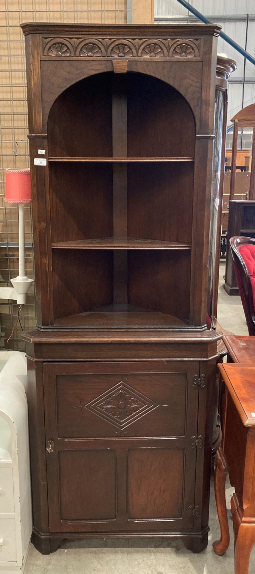 A carved oak standing corner cupboard with three open shelves over single door base,