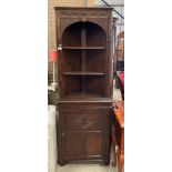 A carved oak standing corner cupboard with three open shelves over single door base,