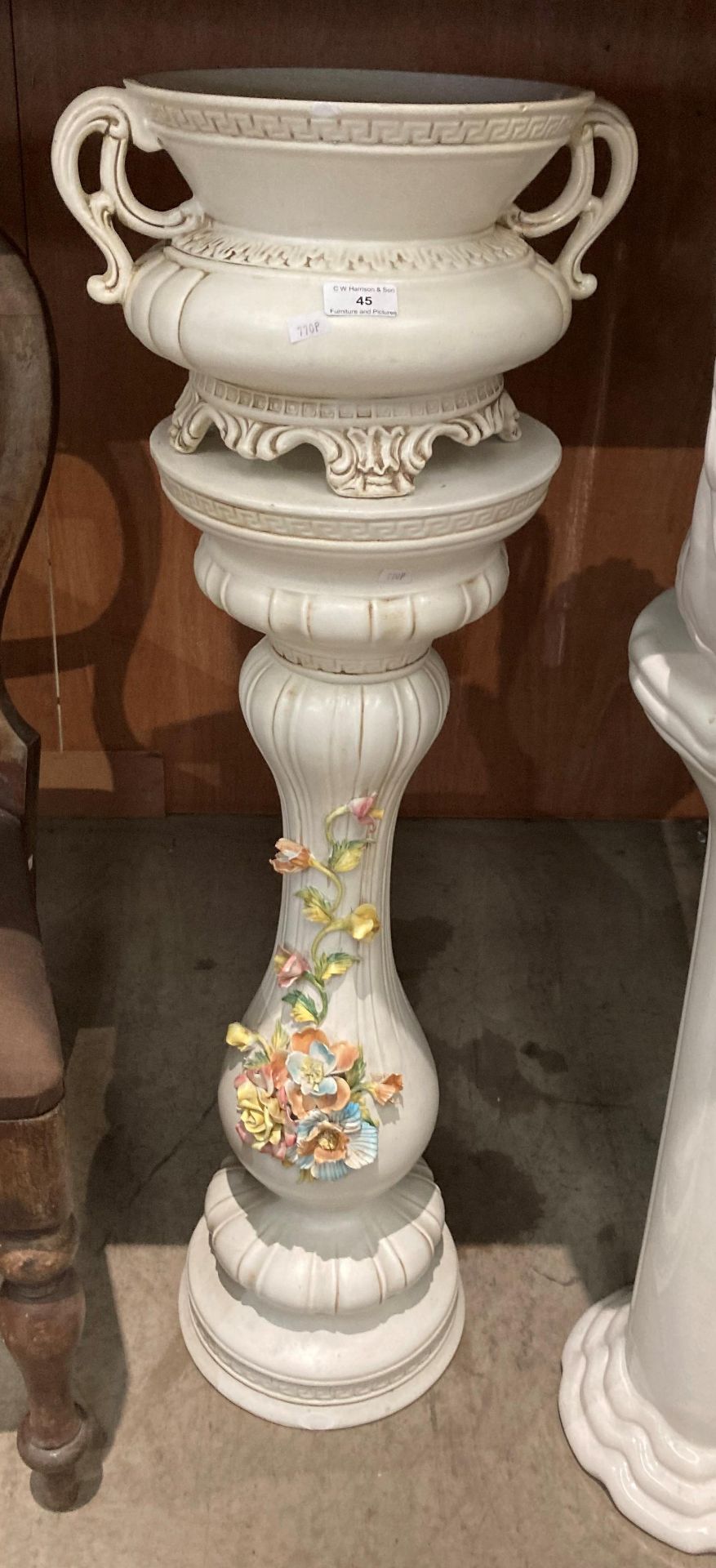 A continental style cream floral decorated jardiniere stand with pottery urn planter on top,