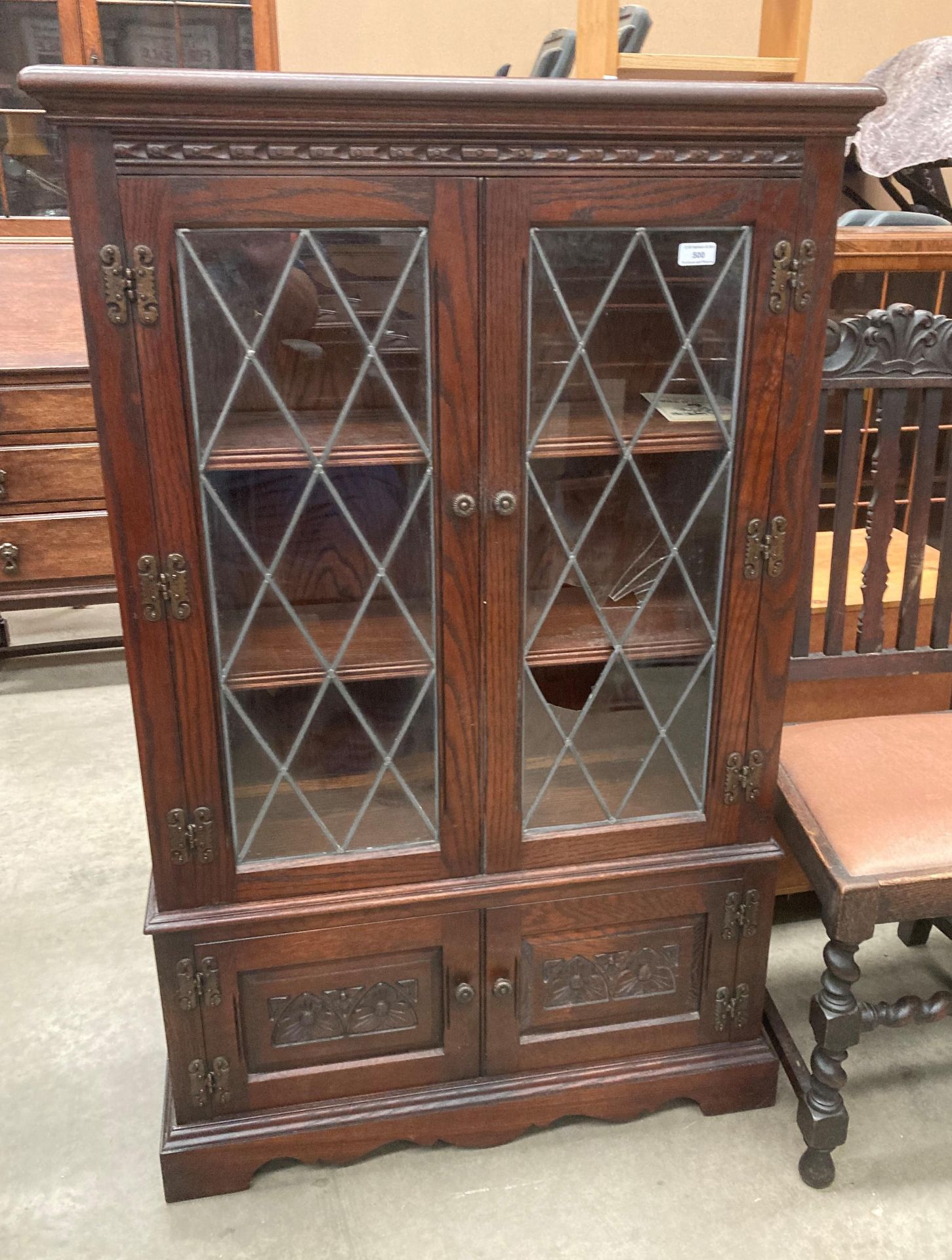 An Old Charm oak display cabinet with two leaded glazed doors (one damaged) over two door base,