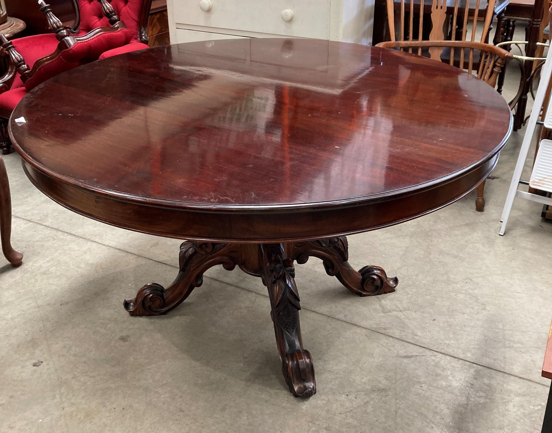 A mahogany Victorian style circular dining table on bulbous centre column support with four carved