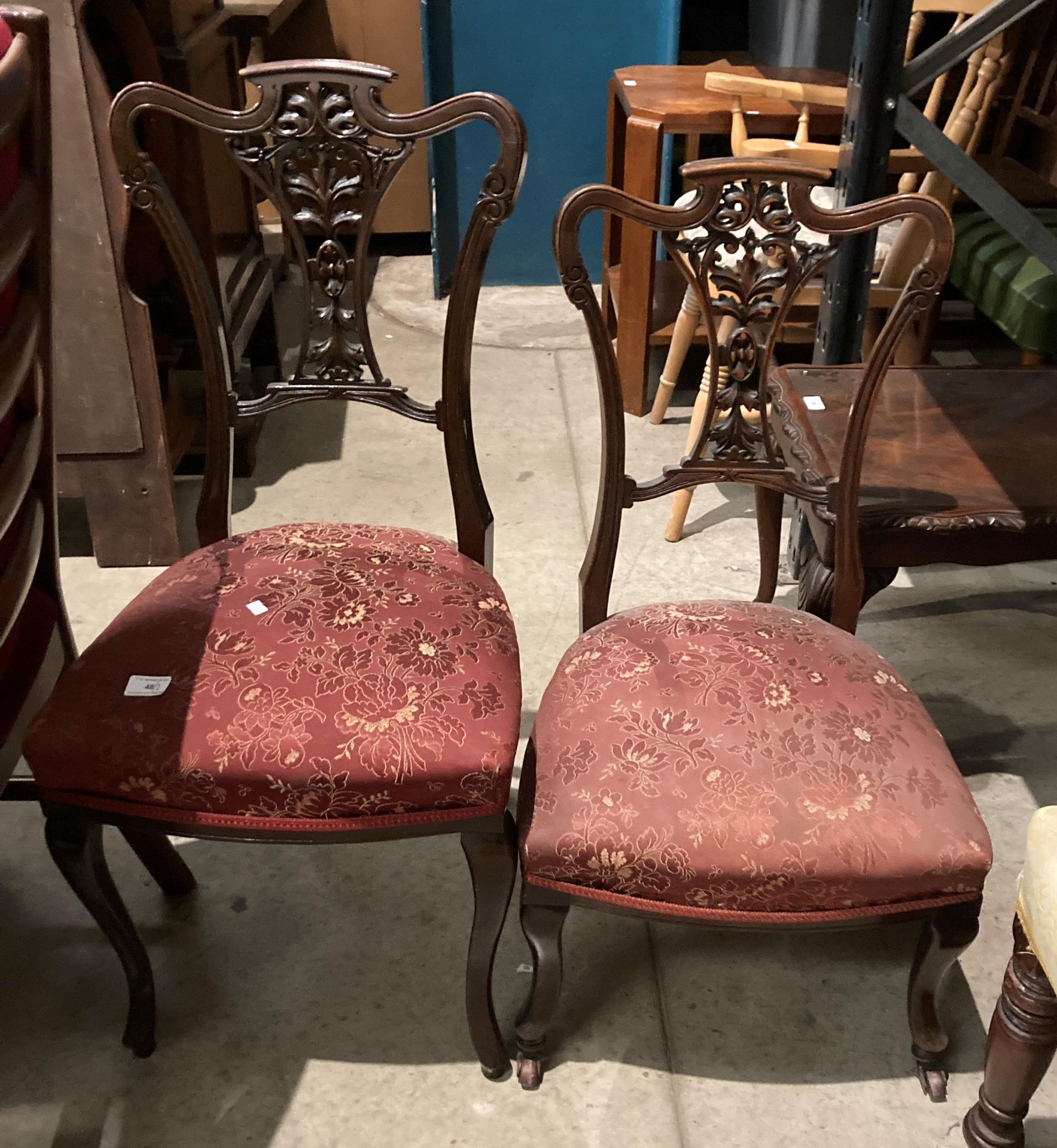 A pair of mahogany salon chairs with carved centre splat back and red patterned fabric seats,