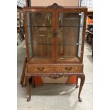 A burr walnut display cabinet with two upper glazed doors over two drawers on cabriole legs,