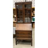 An oak bureau bookcase with two wood lined glazed doors over fall flap two drawer base,