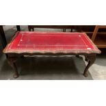 A mahogany framed coffee table on cabriole legs with red tooled leather finish top with glass