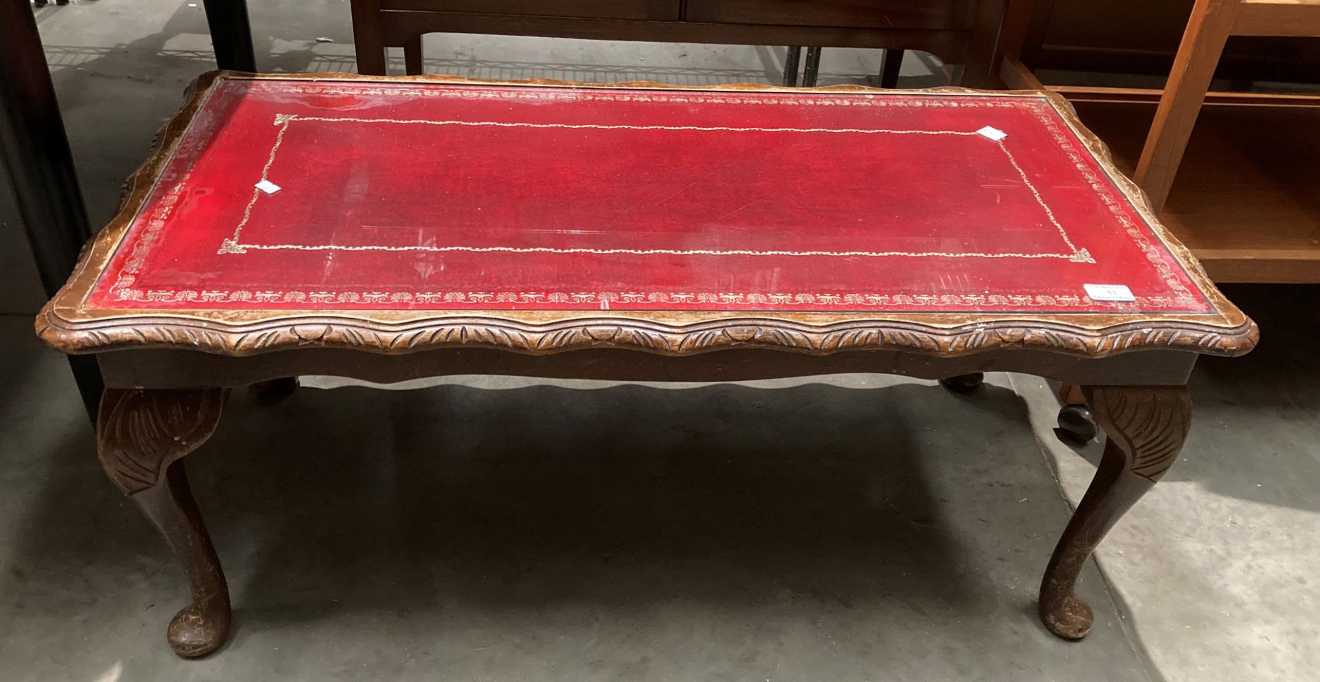 A mahogany framed coffee table on cabriole legs with red tooled leather finish top with glass